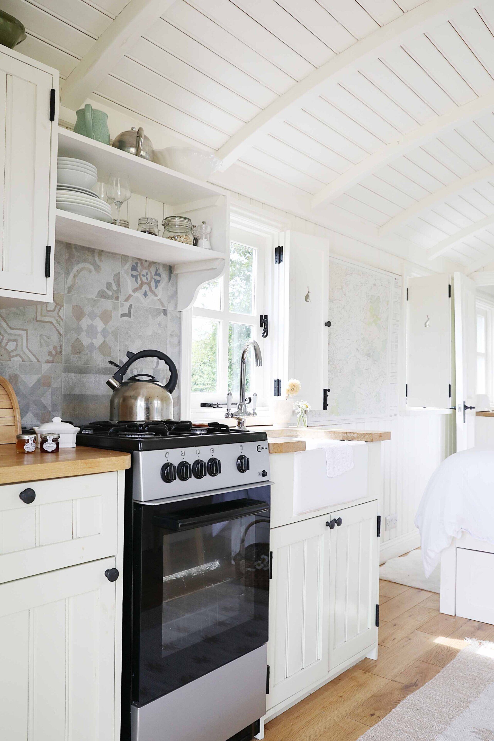 A kitchen with white cabinets, a stove, and a window.