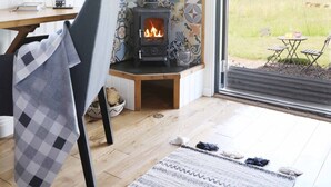 A cozy room with a wood-burning stove, a dining area with a table and chairs, and a view of the outdoors.