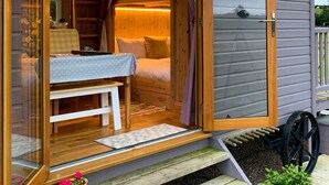 A cozy wooden cabin with a bed, a small table, and a bench.
