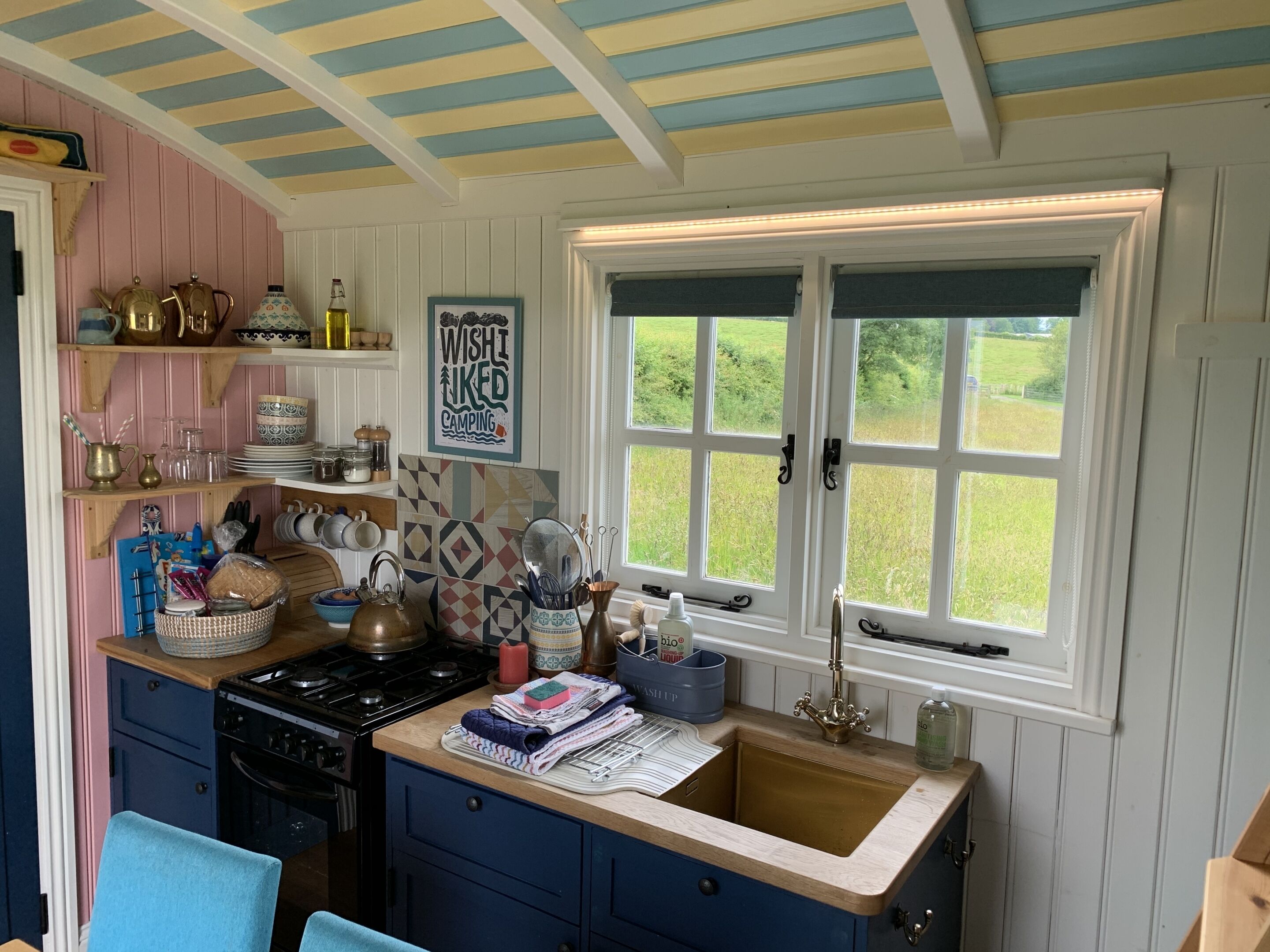 A kitchen with a stove, sink, and window overlooking a garden.