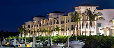 A waterfront hotel with multiple balconies, a marina, and lush greenery.