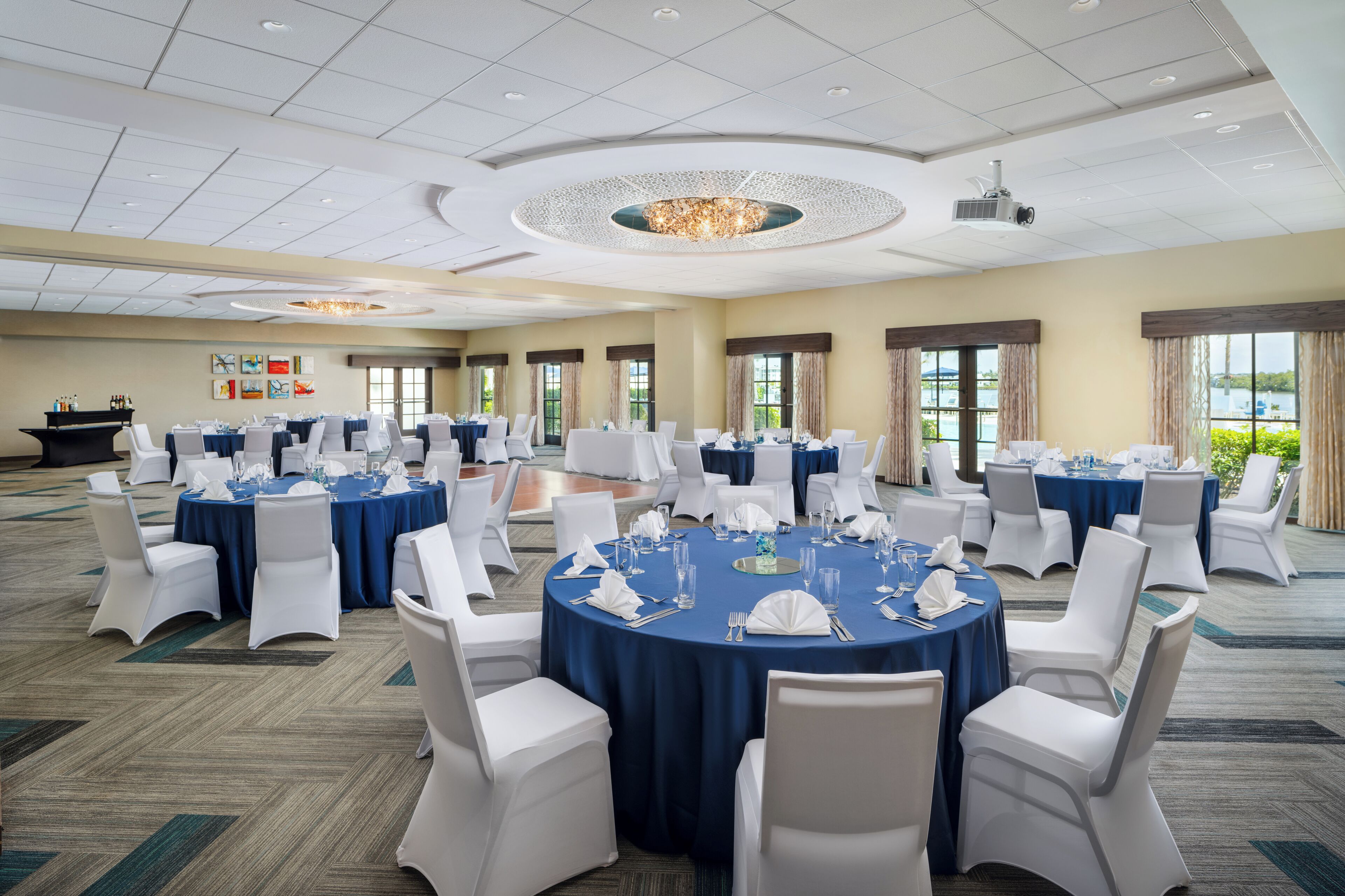 A large conference room with round tables, white chairs, and blue tablecloths.