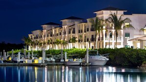 A waterfront hotel with multiple balconies, a marina with boats, and lush greenery.
