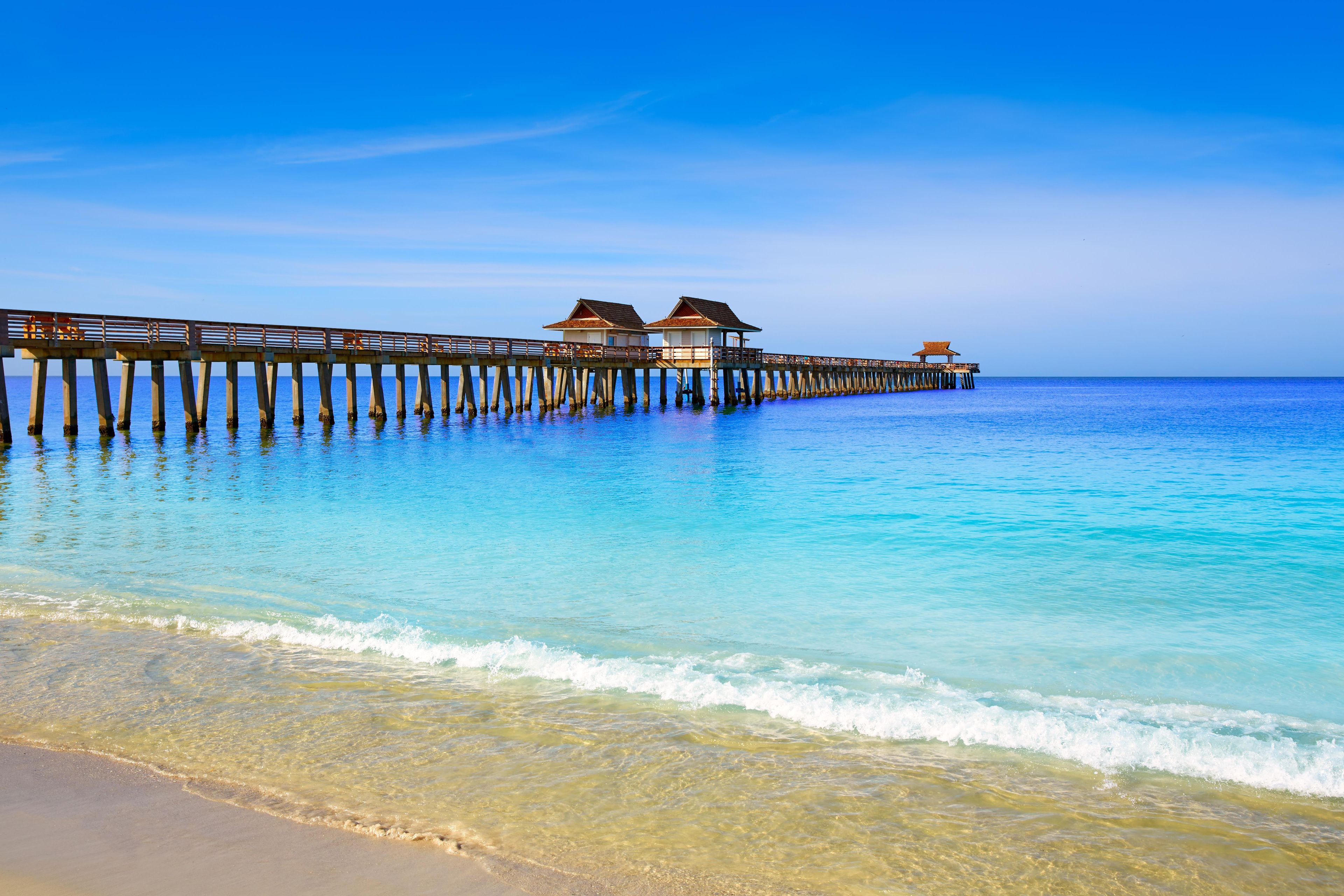 A pier extending into the ocean with overwater bungalows.