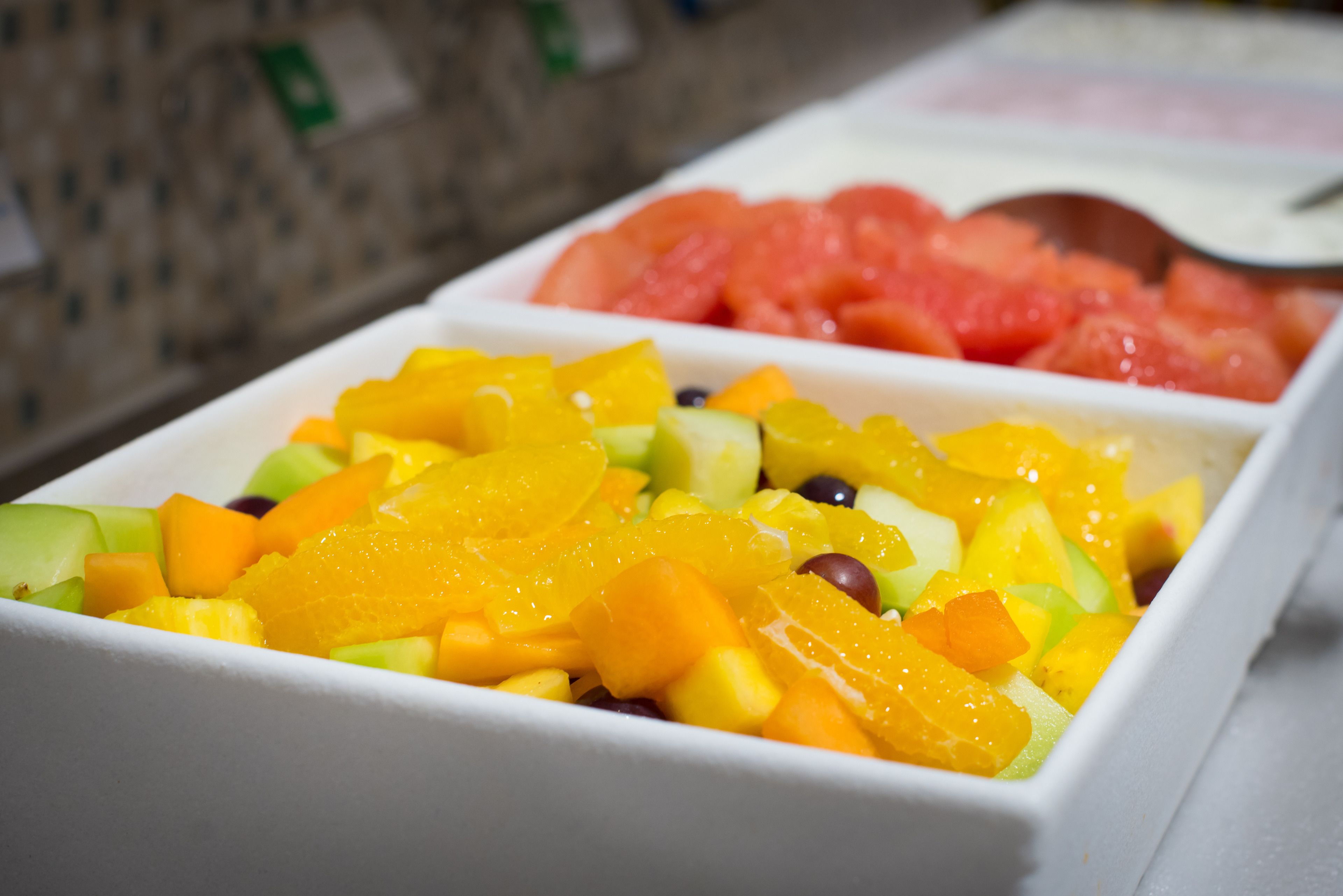 A fruit salad with various fruits in a white bowl.
