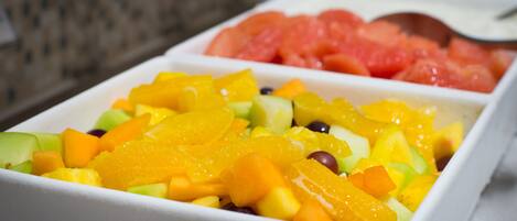 A fruit salad with various fruits in a white bowl.