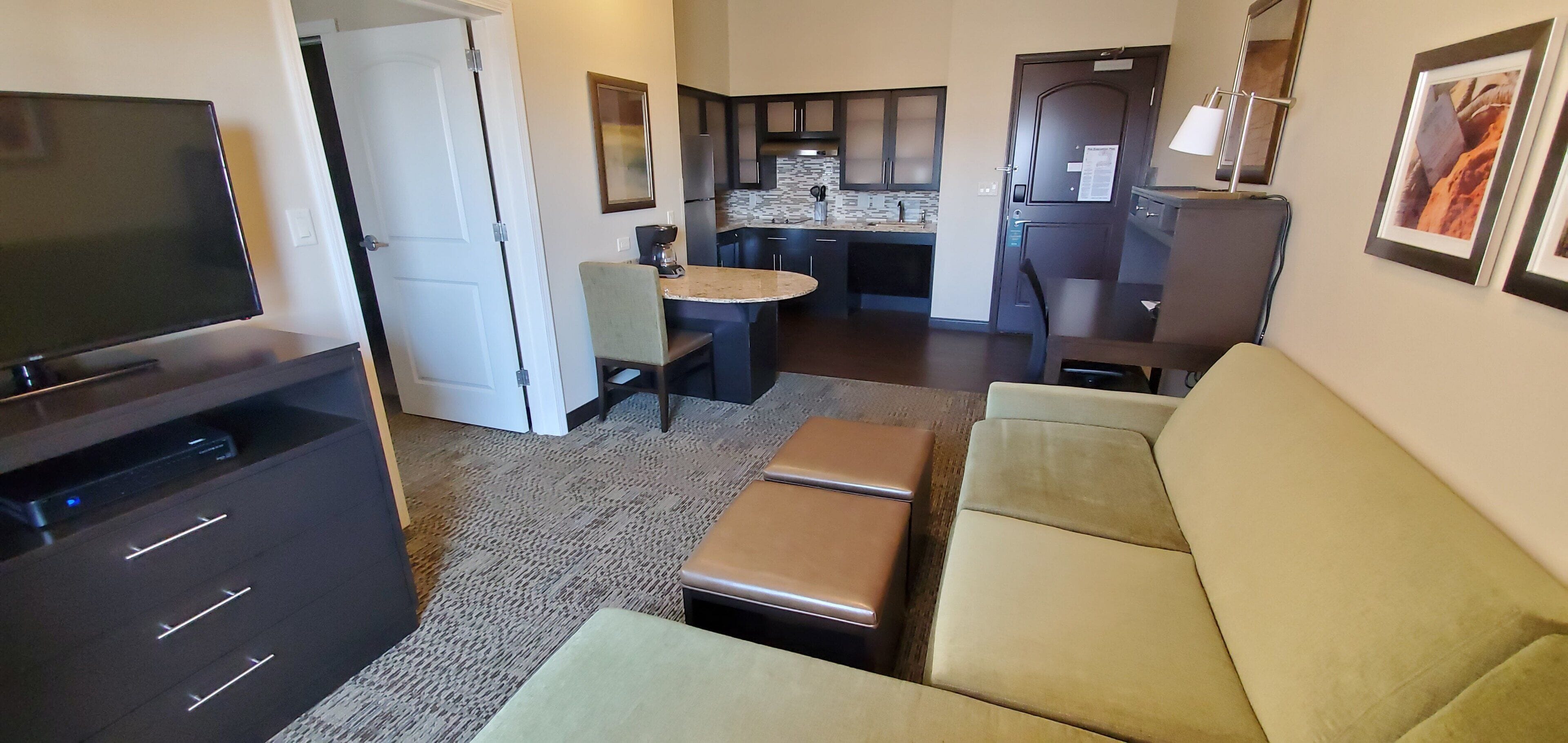 A compact living space with a television, sofa, kitchenette, and a dining area.