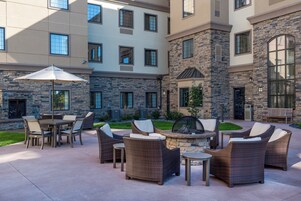 A courtyard with outdoor seating, a fire pit, and a stone building with multiple windows.