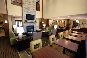 A hotel lobby with a fireplace, seating area, and a bar.