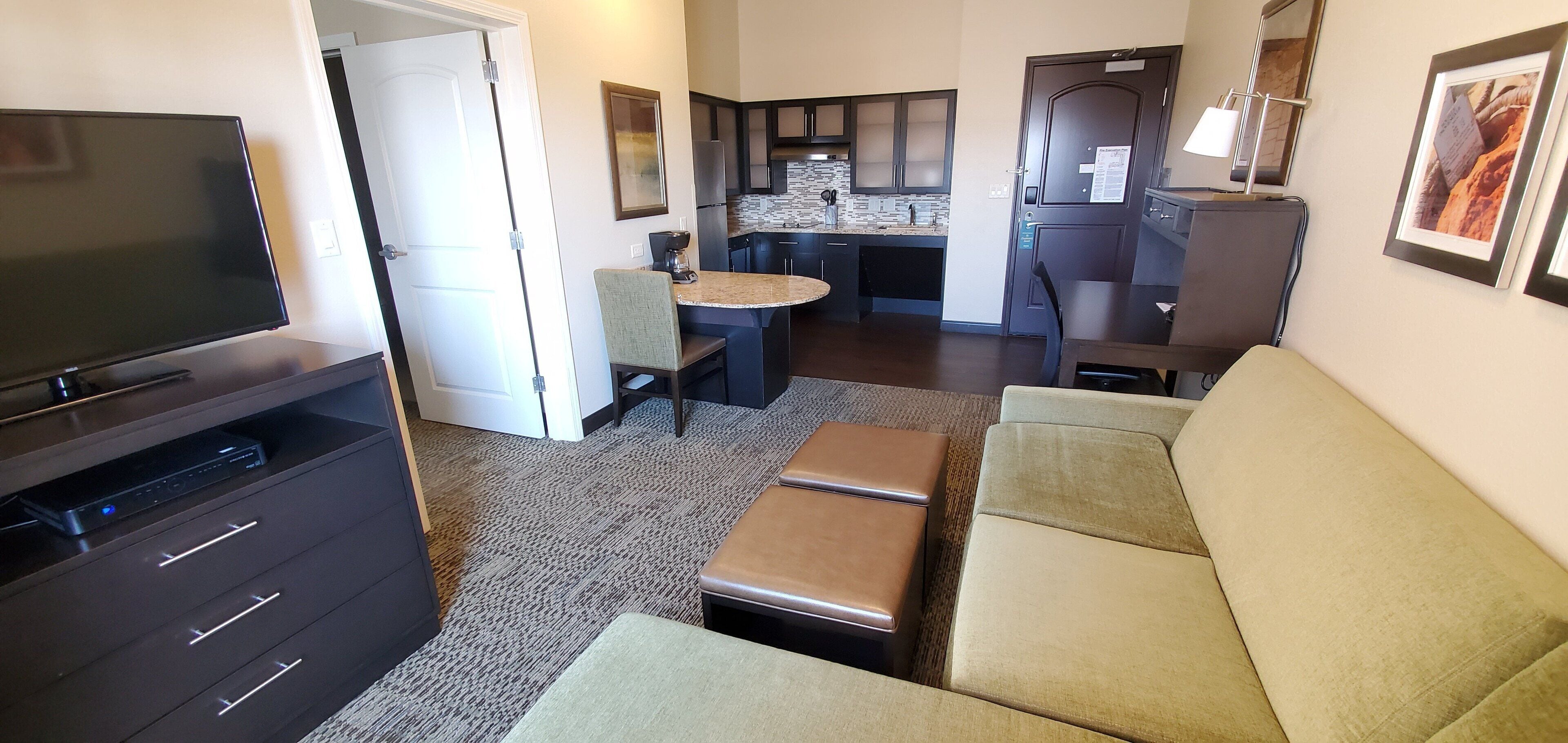 A compact living space with a TV, sofa, and kitchenette.