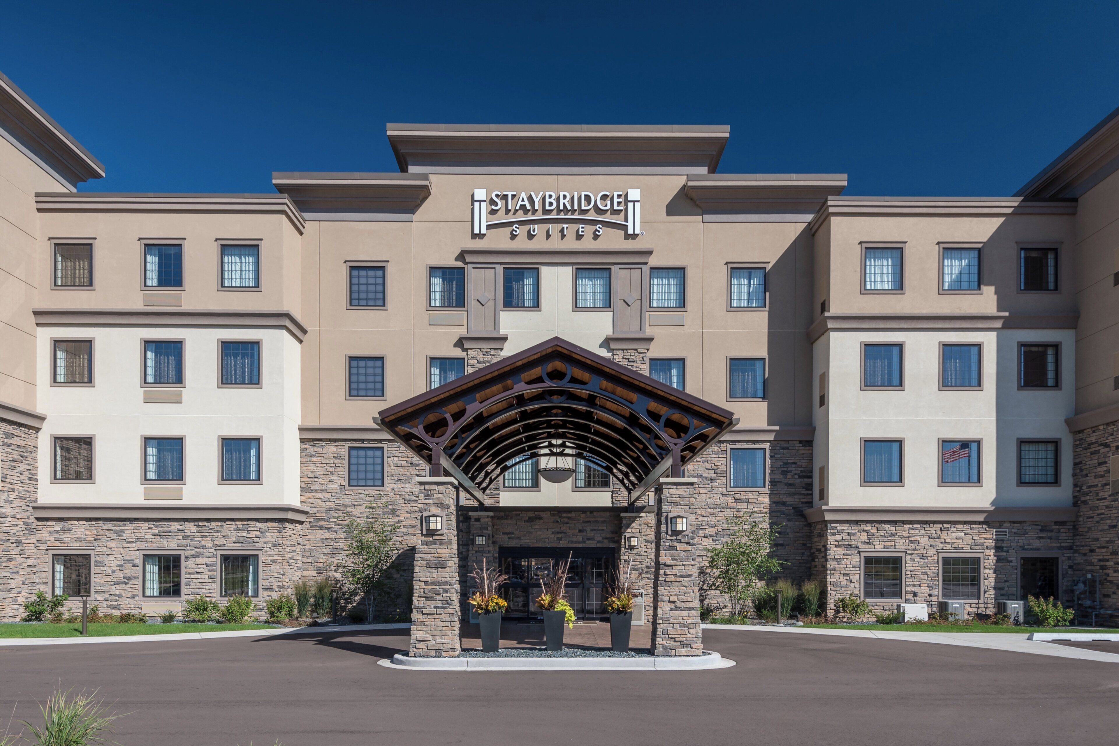 A Staybridge Suites hotel with a stone facade, multiple windows, and a covered entrance.