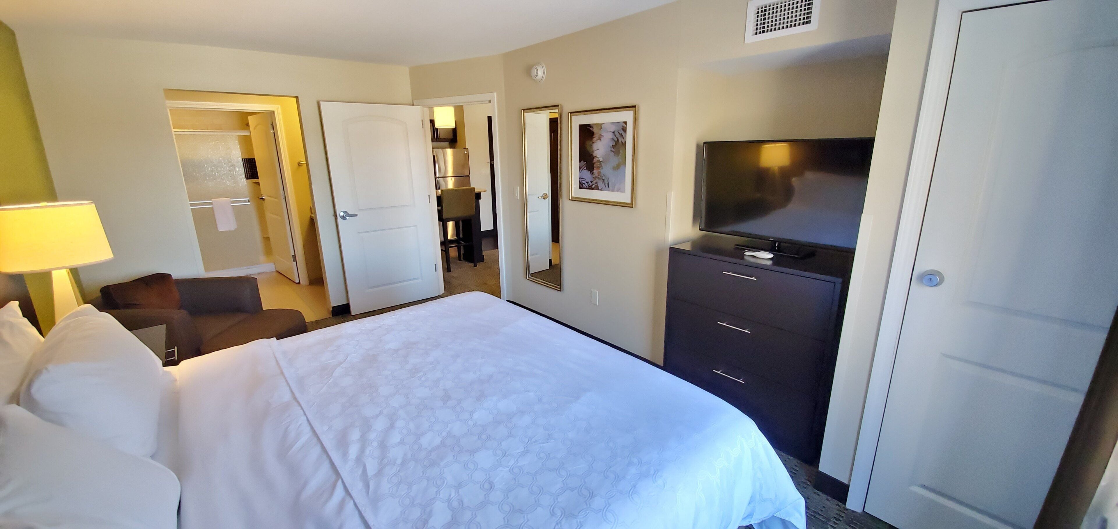 Une chambre d’hôtel comprenant un lit, une télévision, une commode et une porte donnant sur une salle de bain.