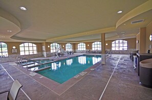 Una piscina interior con varias pistas de natación, una silla de socorrista y un cartel de elevador para spa.