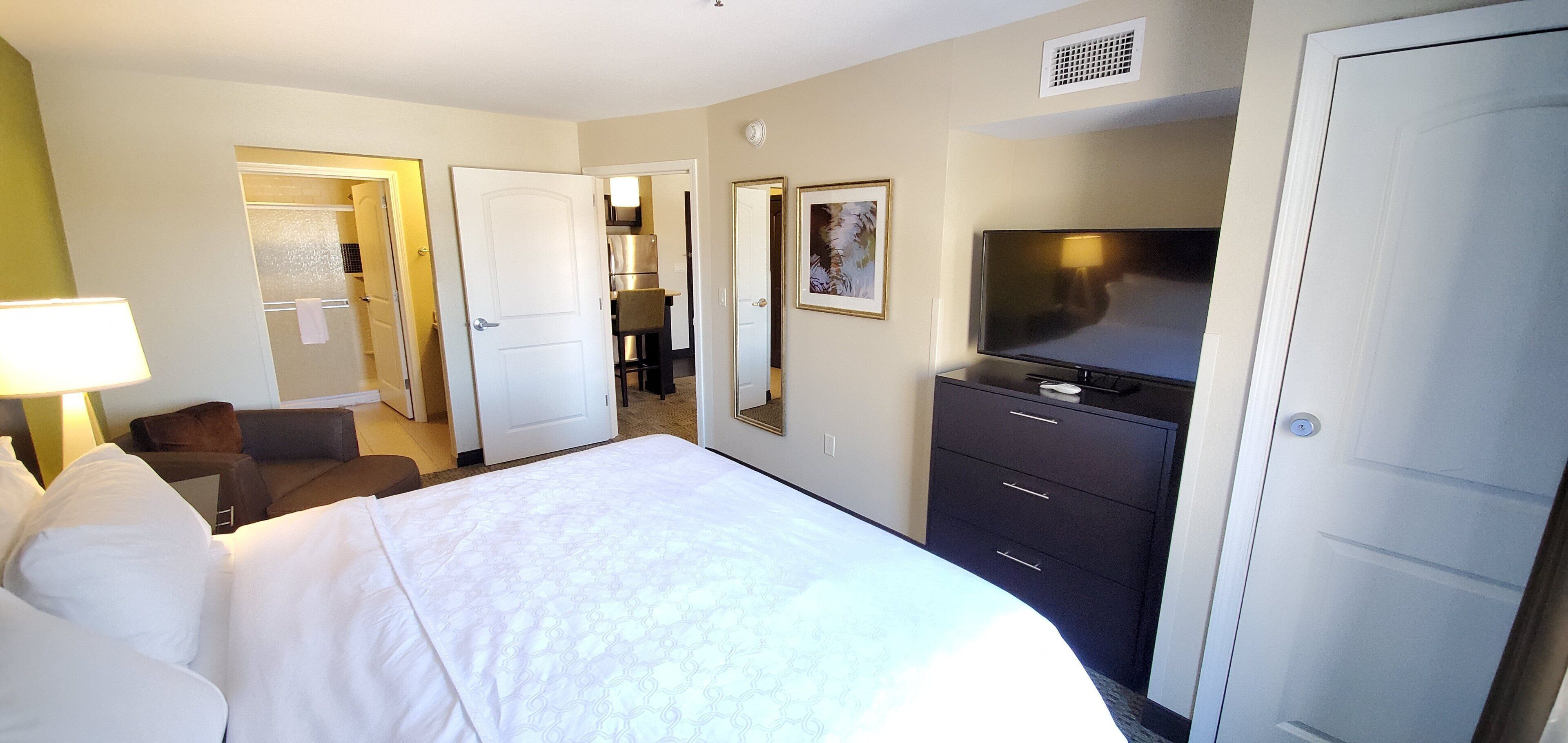 A hotel room with a bed, a desk, a chair, a television, and a wardrobe.