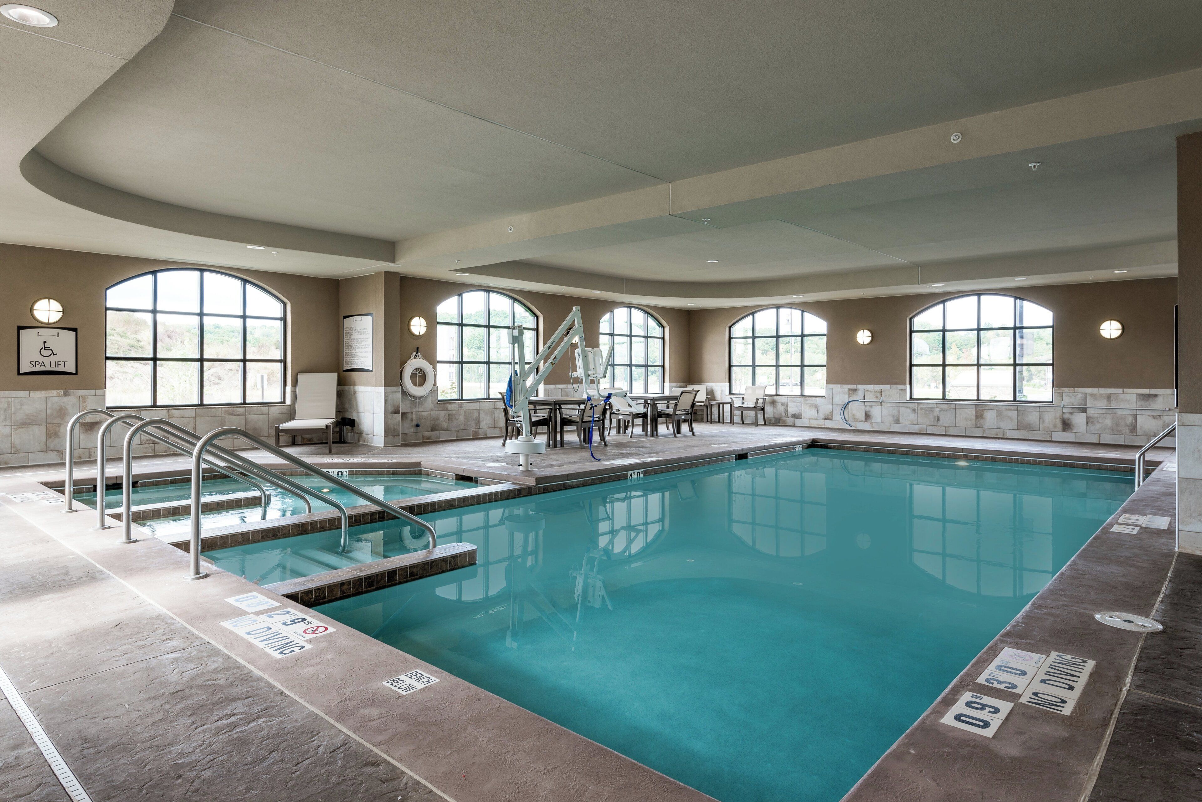 A large indoor swimming pool with clear water, surrounded by lounge chairs and a spa lift.