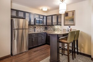 A modern kitchen with stainless steel appliances, dark cabinetry, and a built-in microwave.