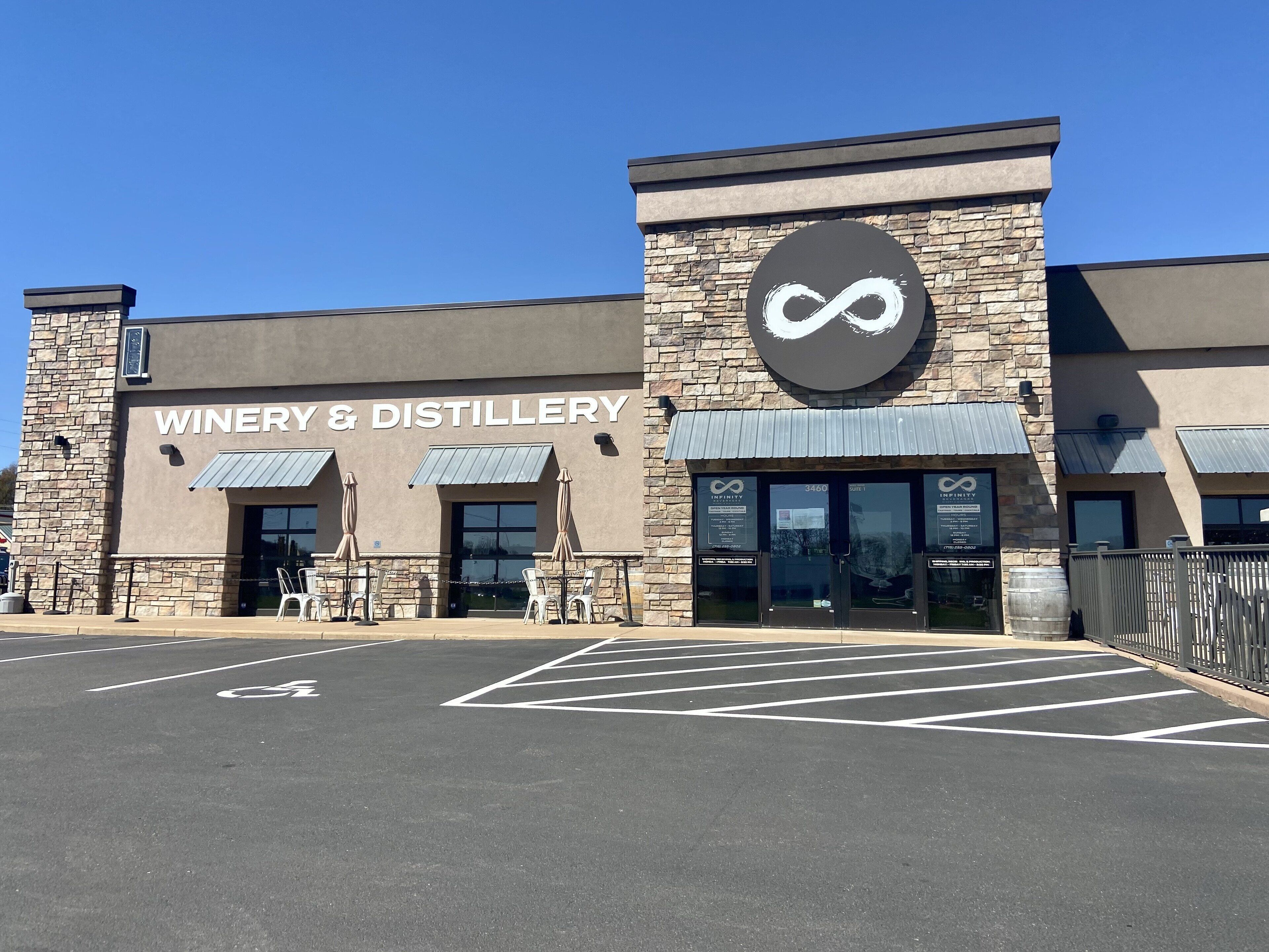 A building with a sign reading "WINERY & DISTILLERY" and a large infinity symbol logo.