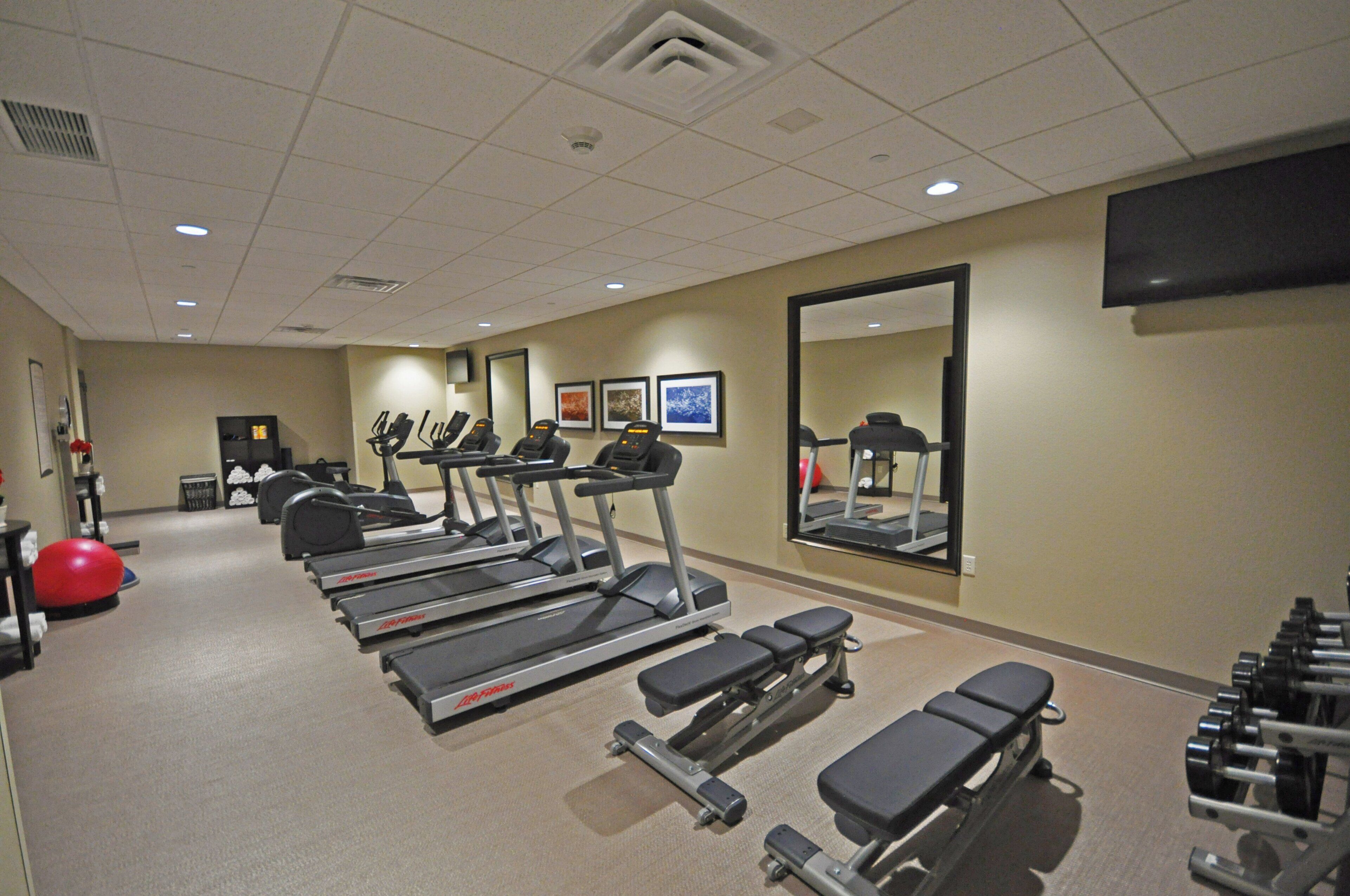 A gym with treadmills, exercise bikes, and a weight bench area.