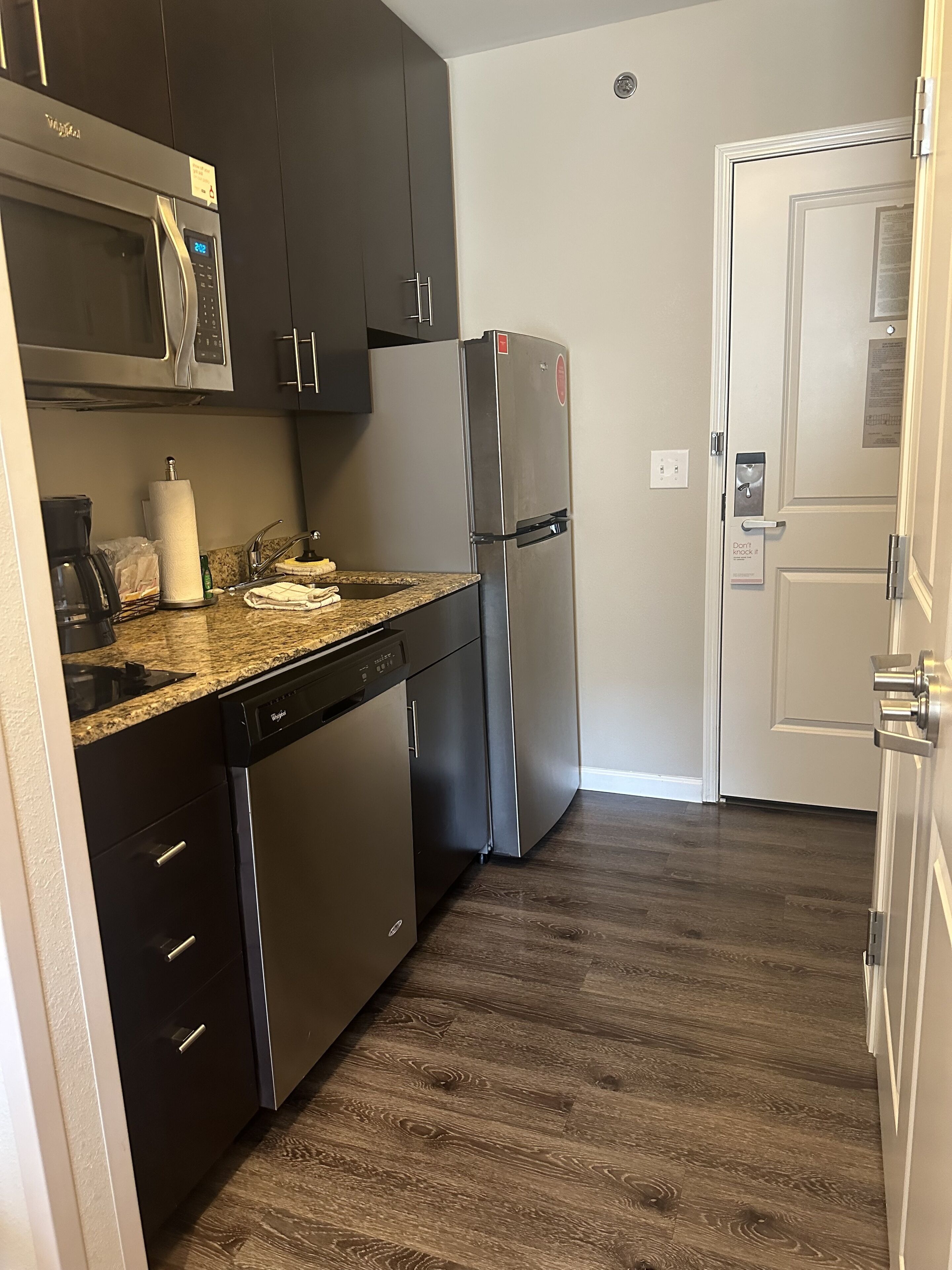 A compact kitchen with a stainless steel refrigerator, a built-in microwave, and a dishwasher.