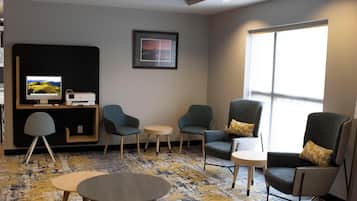 A modern hotel room with a desk, two armchairs, a sofa, and a small table.