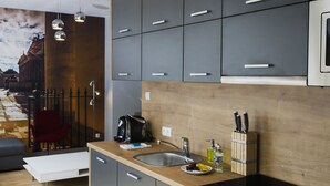 A modern kitchen with grey cabinets, a wooden countertop, and pendant lighting. - Aparthotel Apartments Wrocław (Wroclaw)