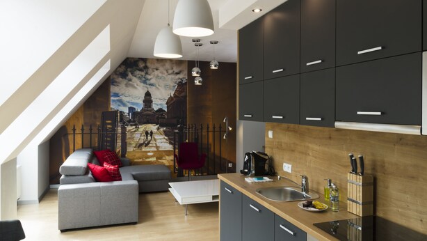 A modern kitchen with dark cabinets, a wooden countertop, and a cityscape mural on the wall. - Aparthotel Apartments Wrocław (Wroclaw)