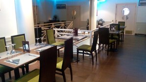 A dining area with tables and chairs, a view of the outside, and a blue-lit ceiling. - Hostal Alcázar (Toledo)