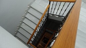 A staircase with wooden handrails and metal balusters leading to a landing. - Hostal Alcázar (Toledo)