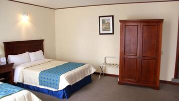 Habitación de hotel con una cama grande, un armario, una mesita de noche y una lámpara en la pared.