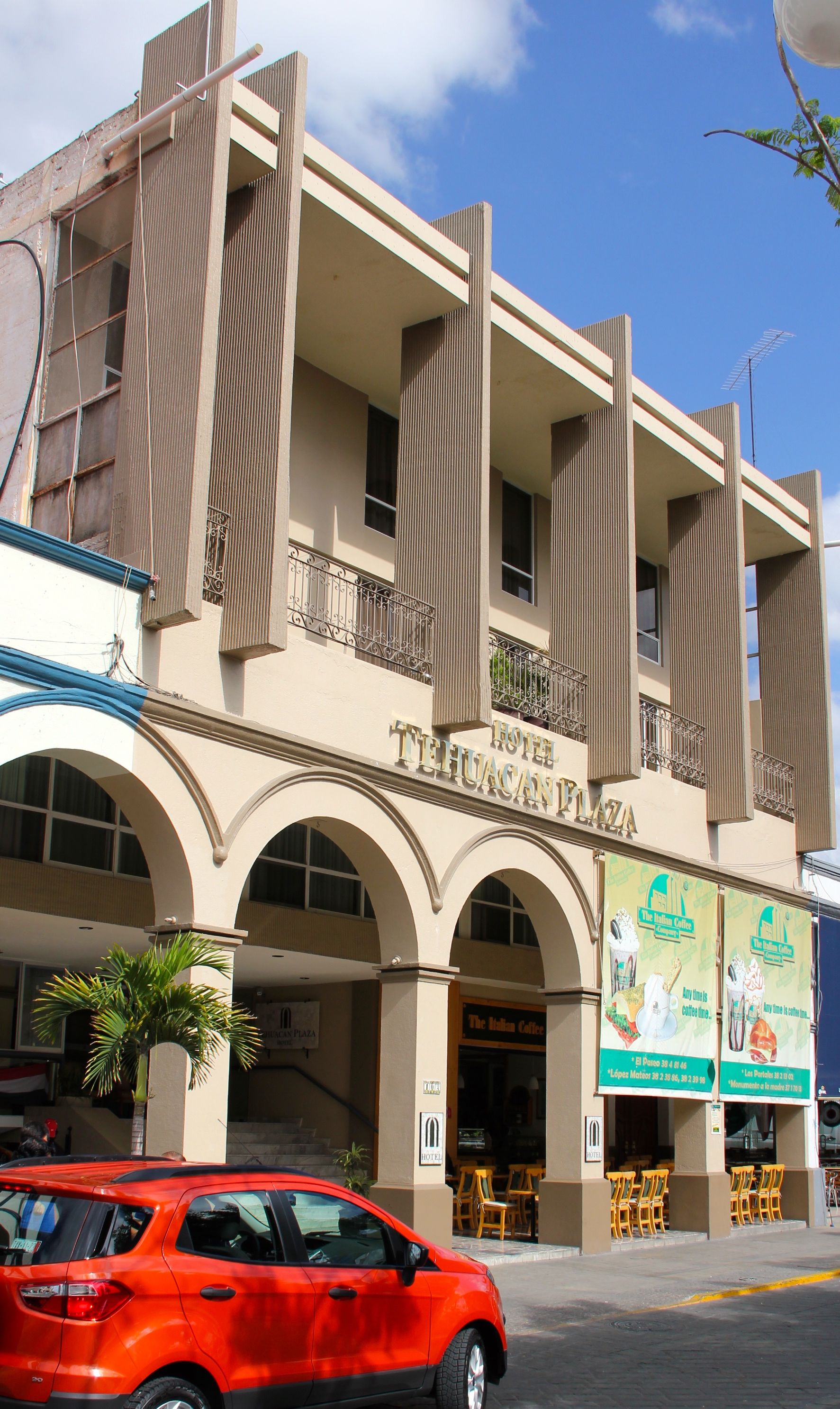 Un hotel con fachada moderna, varios balcones y un letrero que dice 'The Italian Coffee'.