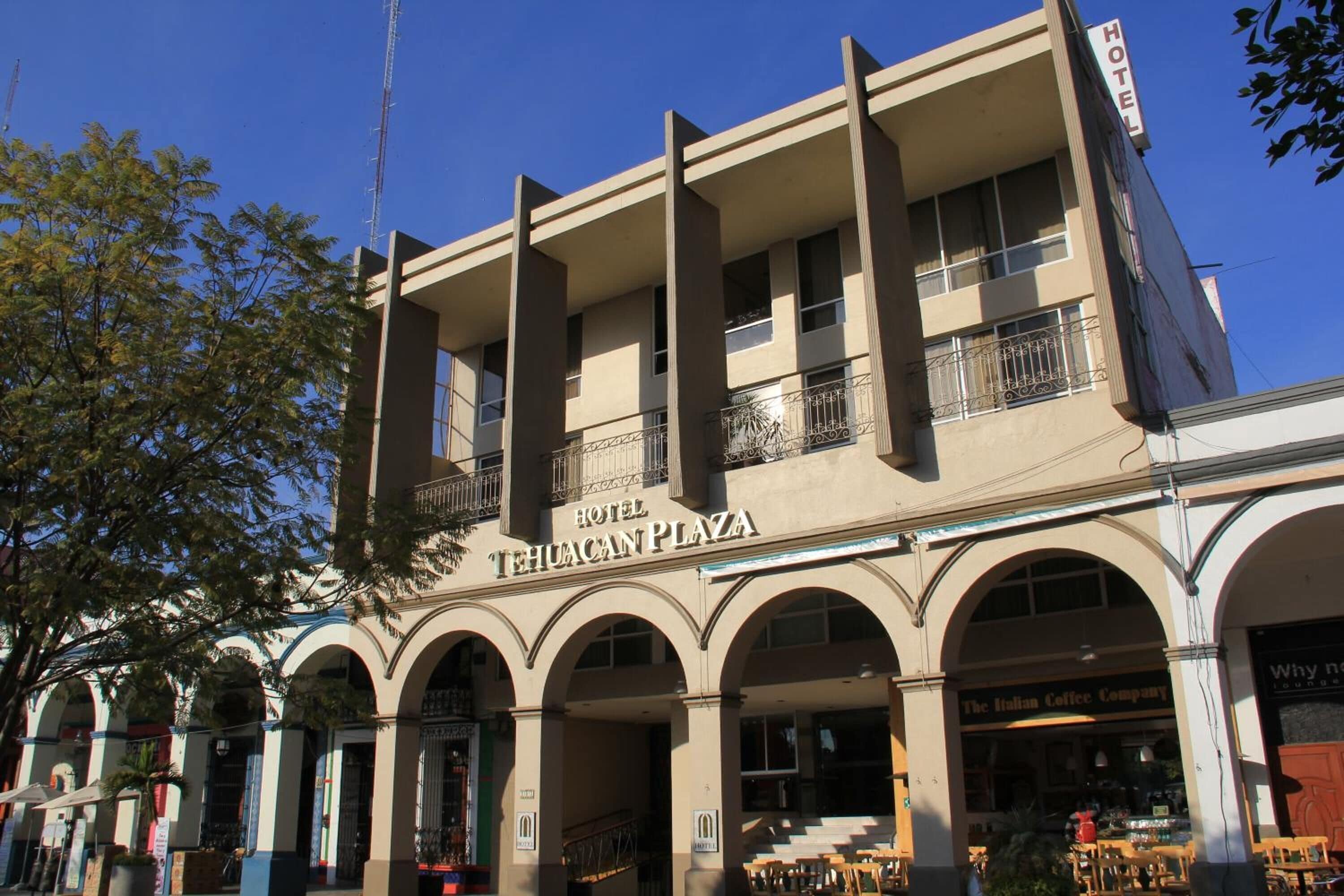 A hotel with a sign reading "HOTEL TEHUACAN PLAZA" and an Italian coffee shop in the foreground.