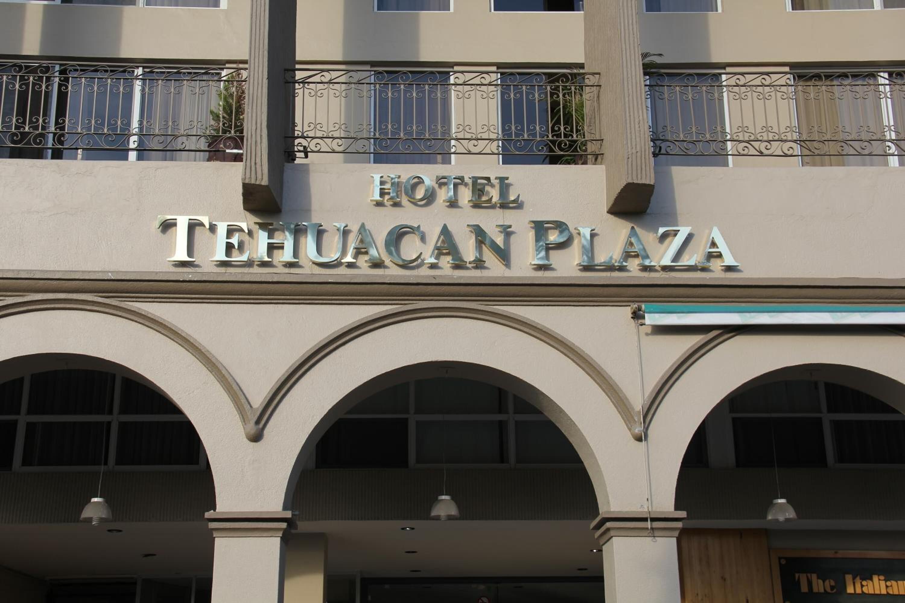 Das Hotel Tehuacan Plaza mit auffälliger Beschilderung und Rundbogenfenstern.