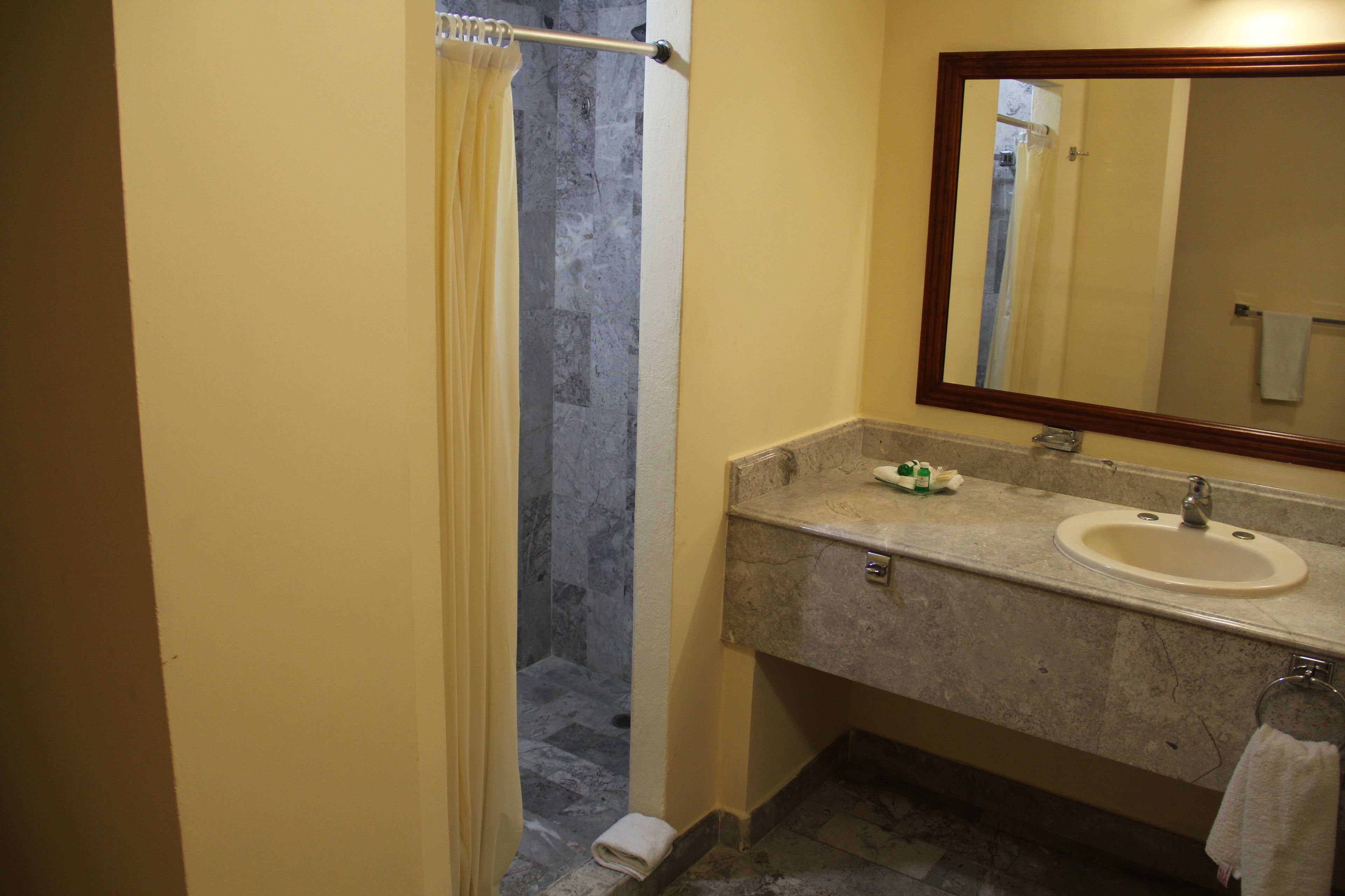 Un baño con ducha, lavamanos y espejo.