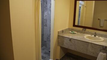 Un baño con ducha, lavamanos y espejo.