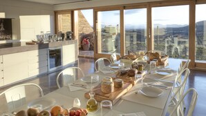 A modern dining area with a table set for four, featuring a variety of fruits, cheeses, and bread. - Trossos del Priorat (Gratallops)