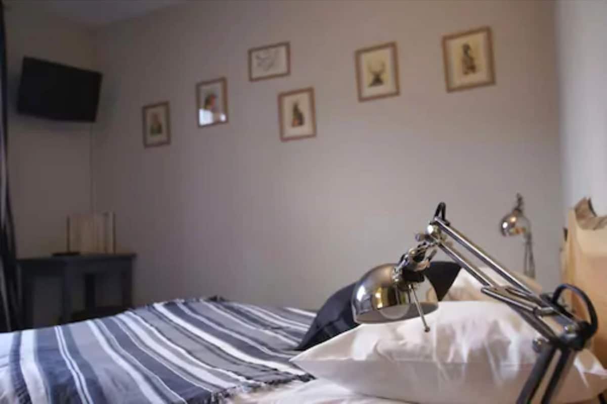 A bedroom with a bed, a bedside lamp, and framed pictures on the wall.