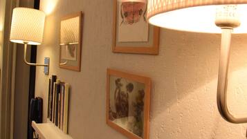 A hallway with a white wall, a white shelf, and three framed pictures.