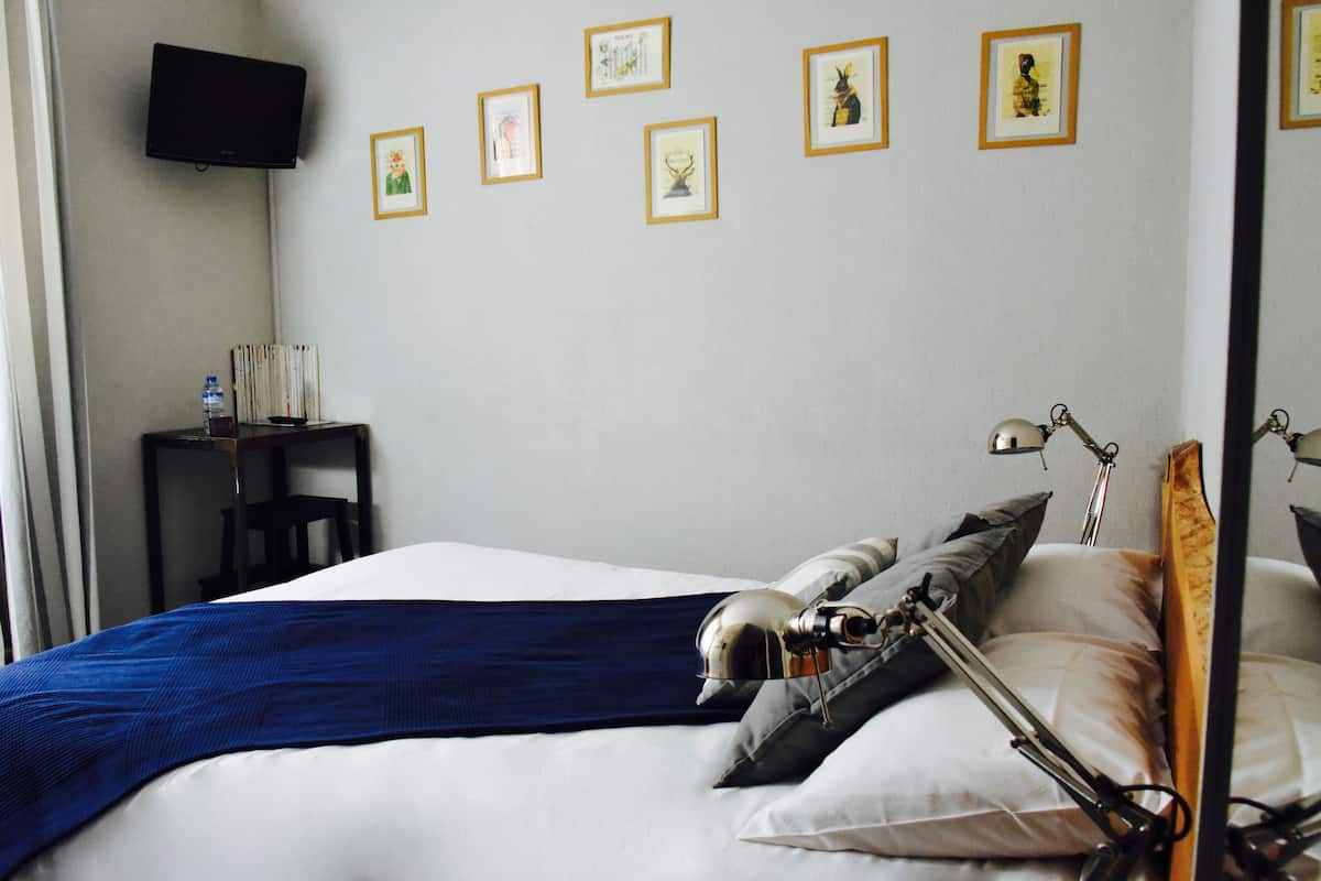 A hotel room with a bed, bedside lamp, and a wall-mounted TV.