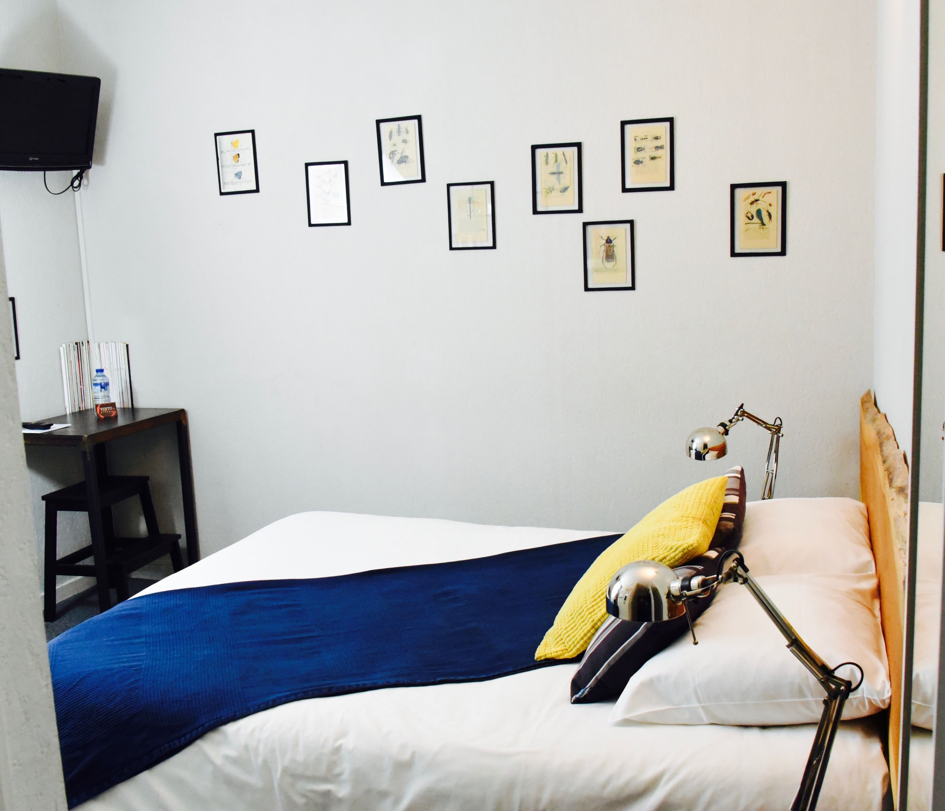 Een hotelkamer met een bed, een bureau, een stoel, een lamp en kunst aan de muur.