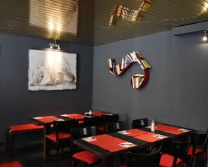 A conference room with a polar bear painting, a bookshelf, and red and black furnishings. - Hotel de La Placette (Barcelonnette)