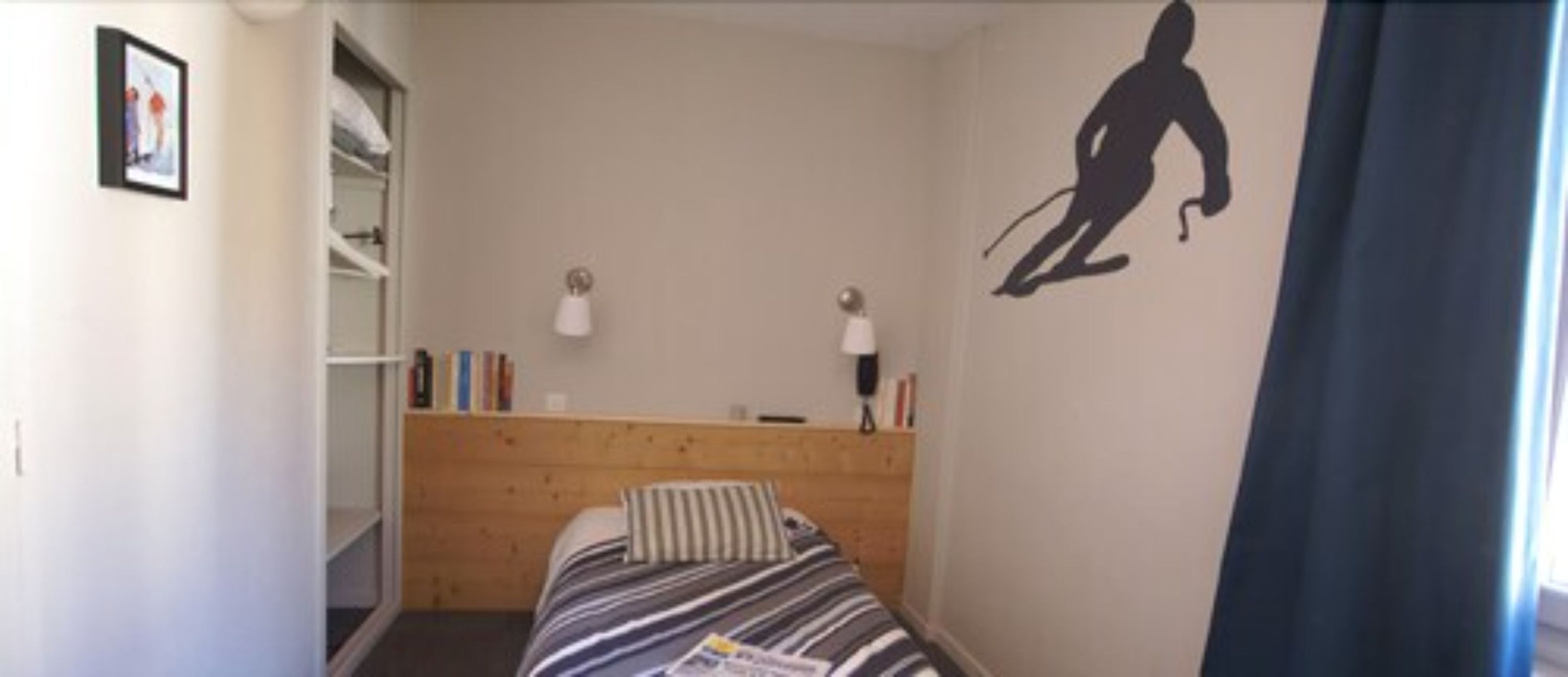 Un dormitorio con cama, cabecera de madera, lámpara de pared y decoración con temática de esquí.