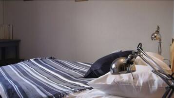 A neatly made bed with striped bedding, a bedside lamp, and a wooden headboard.