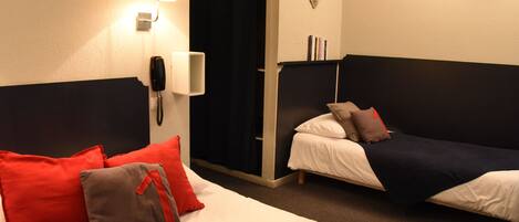 Quarto de hotel com duas camas, um telefone, uma luminária e uma decoração em formato de coração na parede.
