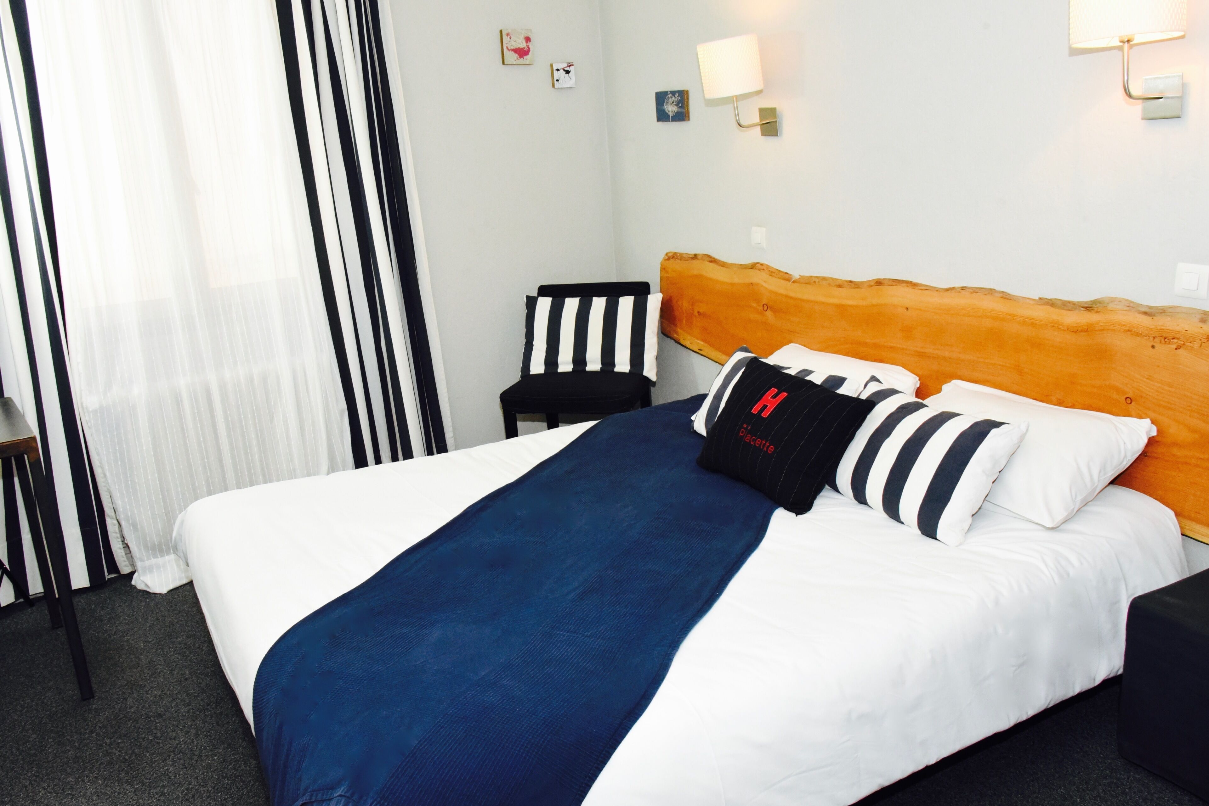 Una habitación de hotel con una cama, una silla y una mesita de noche.