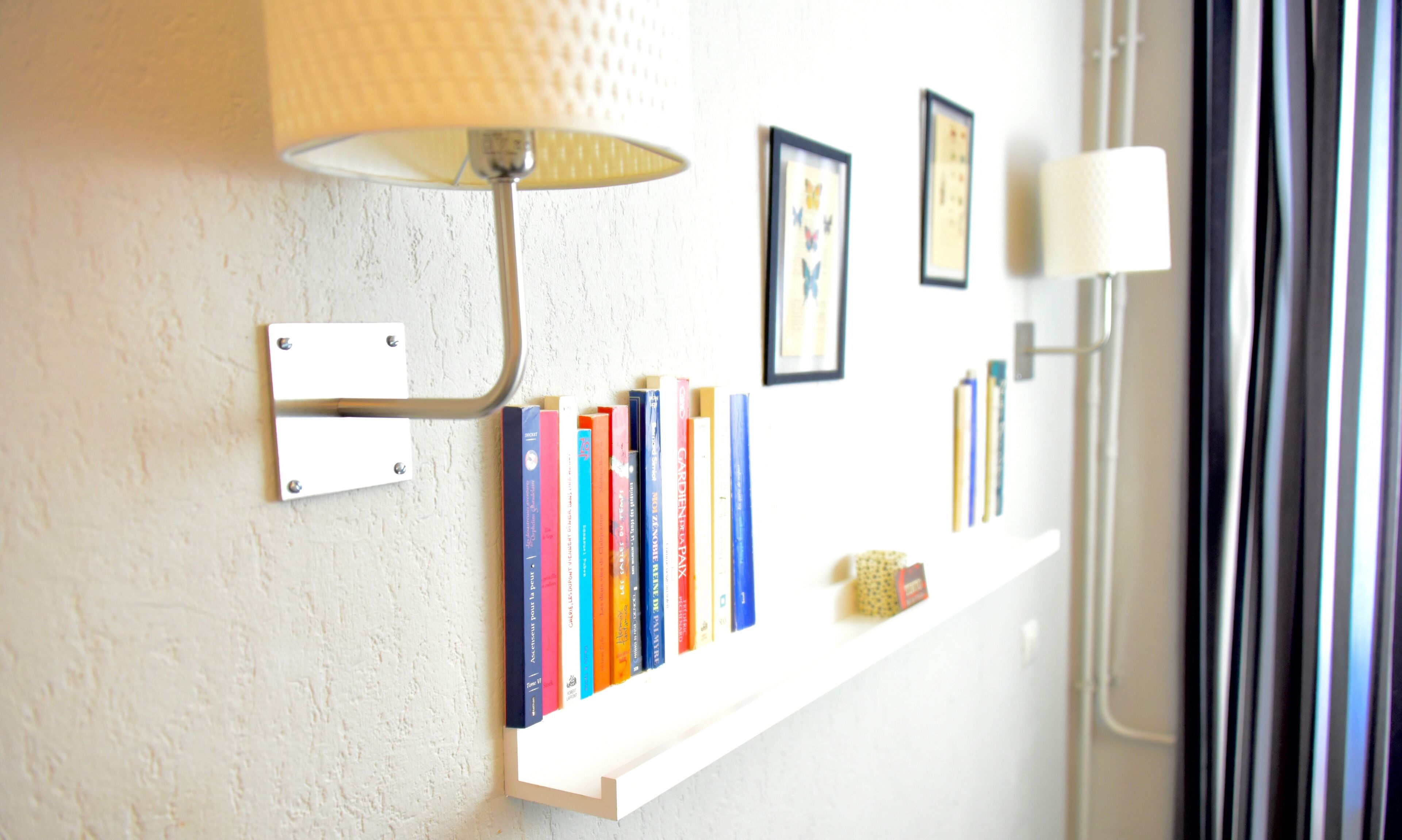 Una mensola a muro con libri e una lampada.