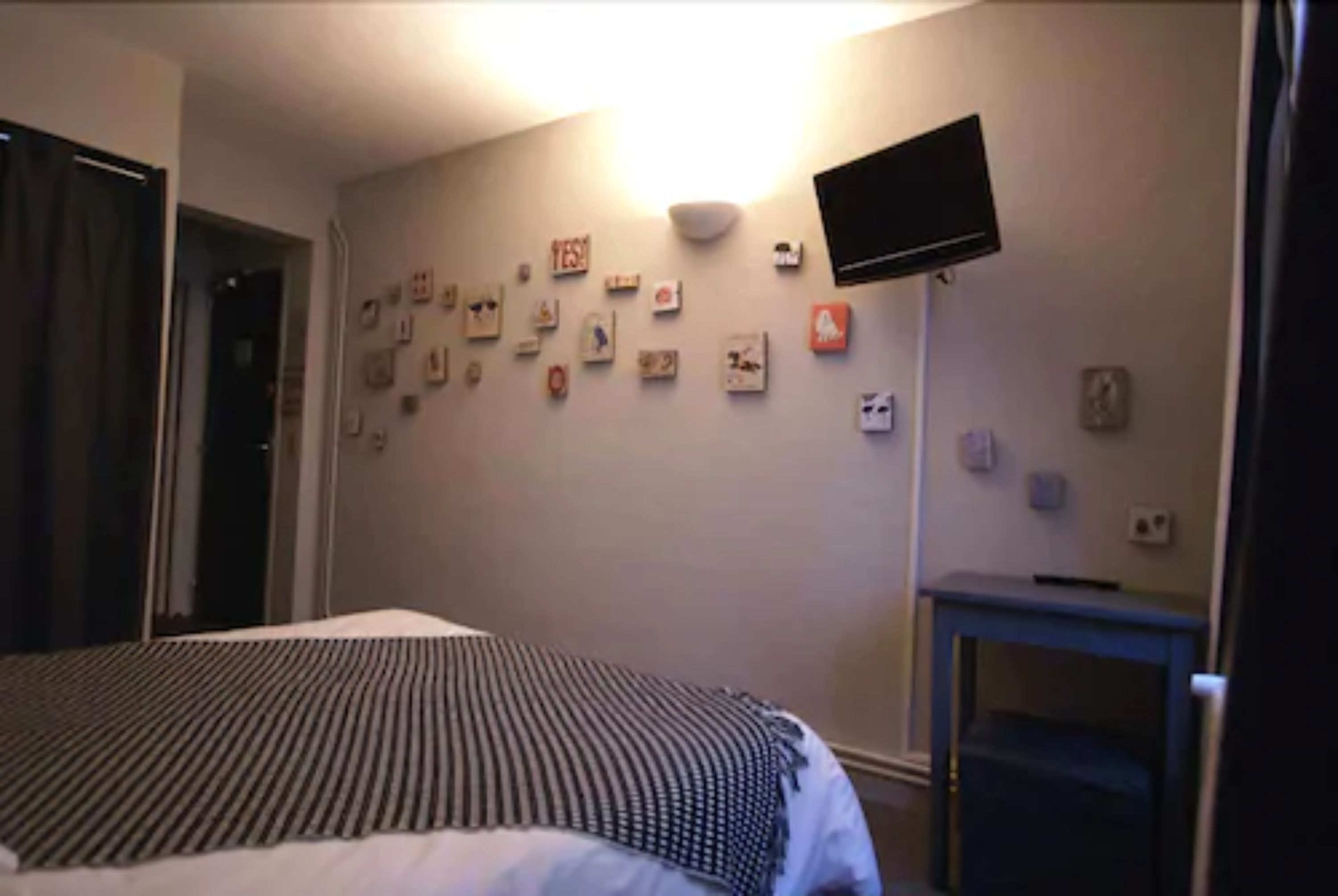 Une chambre d’hôtel avec un lit, un téléviseur à écran plat fixé au mur et une petite table.