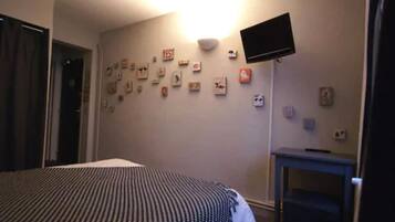 Une chambre d’hôtel avec un lit, un téléviseur à écran plat fixé au mur et une petite table.