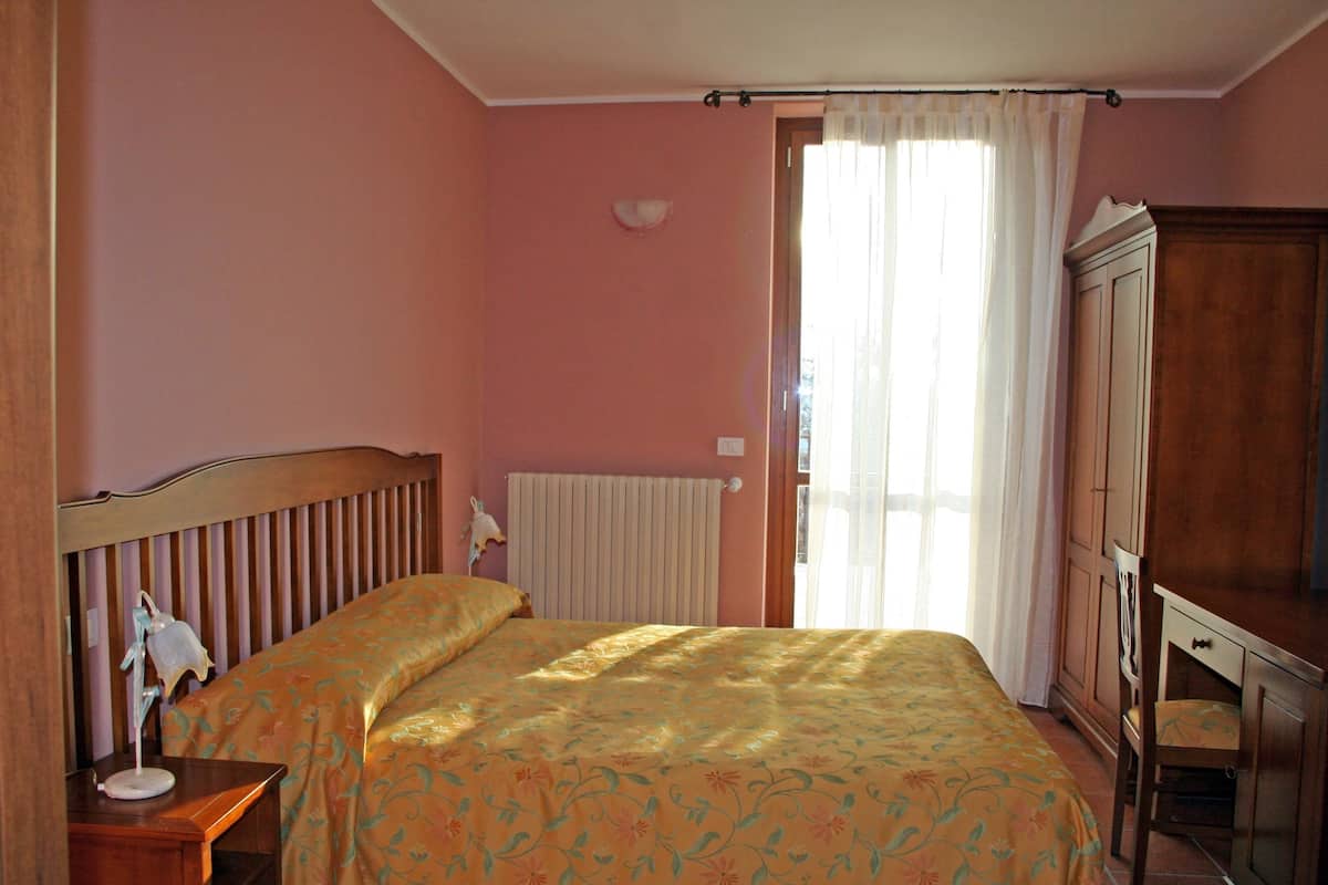 Un dormitorio con cama, mesita de noche, armario de madera y radiador.