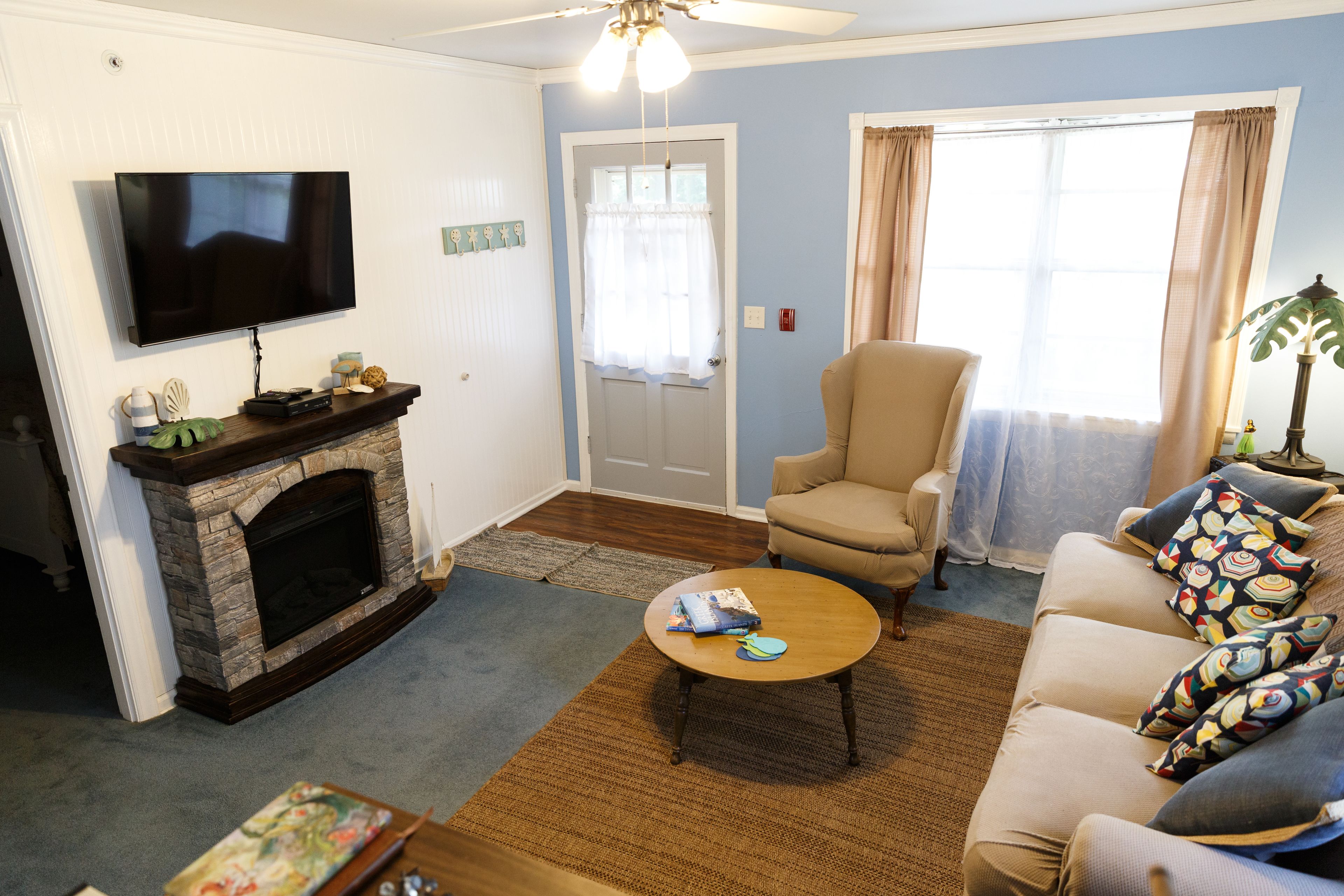 A living room with a fireplace, a television mounted on the wall, a sofa, a coffee table, and a chair.