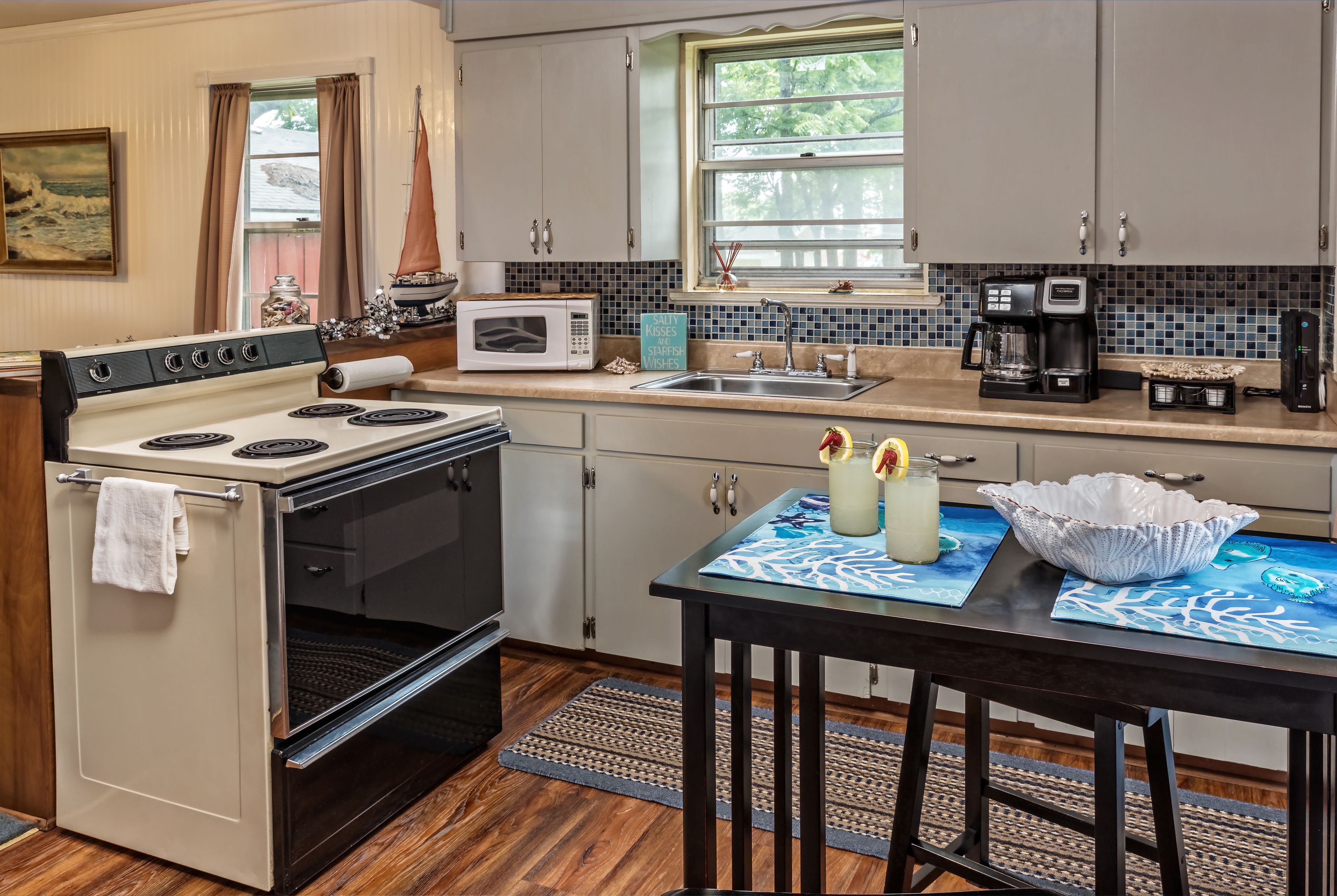 A kitchen with a stove, microwave, sink, and coffee maker.